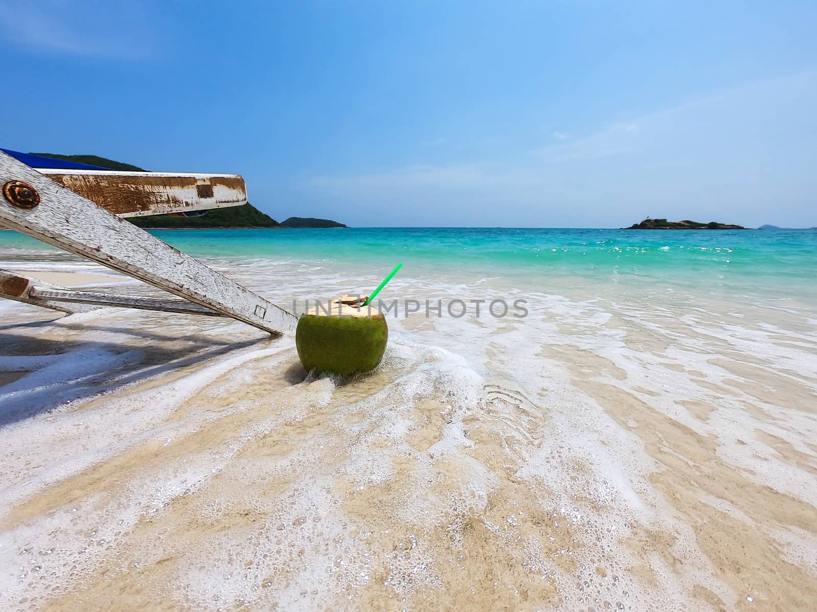Relax beach chair with fresh coconut on clean sand beach with blue sea and clear sky - sea nature background relax concept by pairhandmade