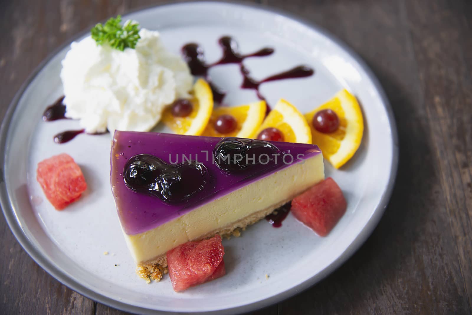 Colorful cheese cake blueberry favor with well decorated fruit pieces and whipped cream in white plate - cake recipe menu concept
