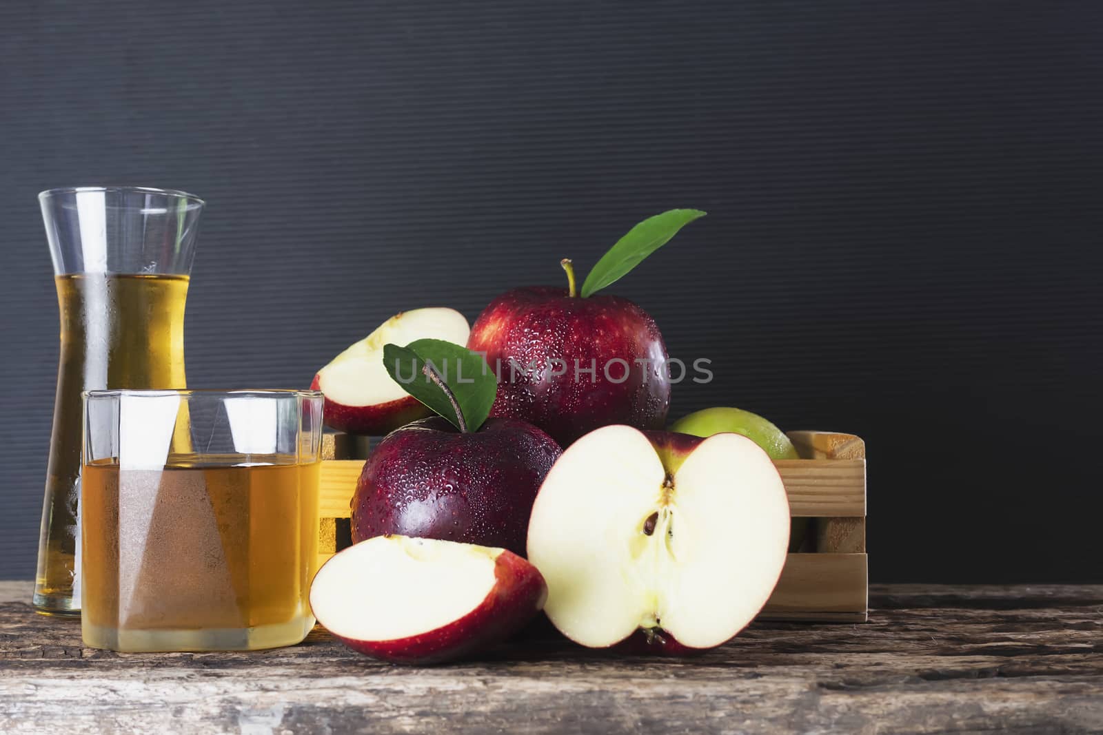 Fresh apple in wooden box with apple juice over black background - fresh fruit and juice product background concept