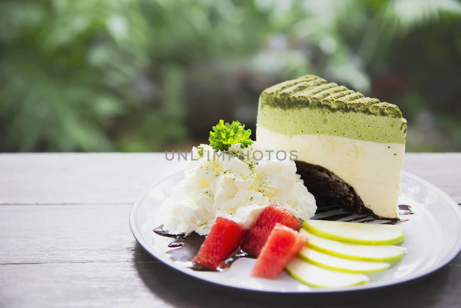 Colorful green tea favor cake with well decorated fruit pieces and whipped cream in white plate - cake recipe menu concept