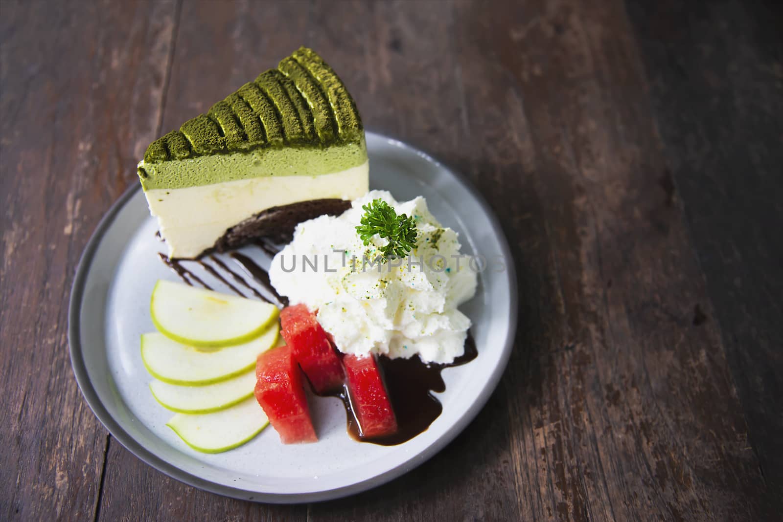 Colorful green tea favor cake with well decorated fruit pieces and whipped cream in white plate - cake recipe menu concept