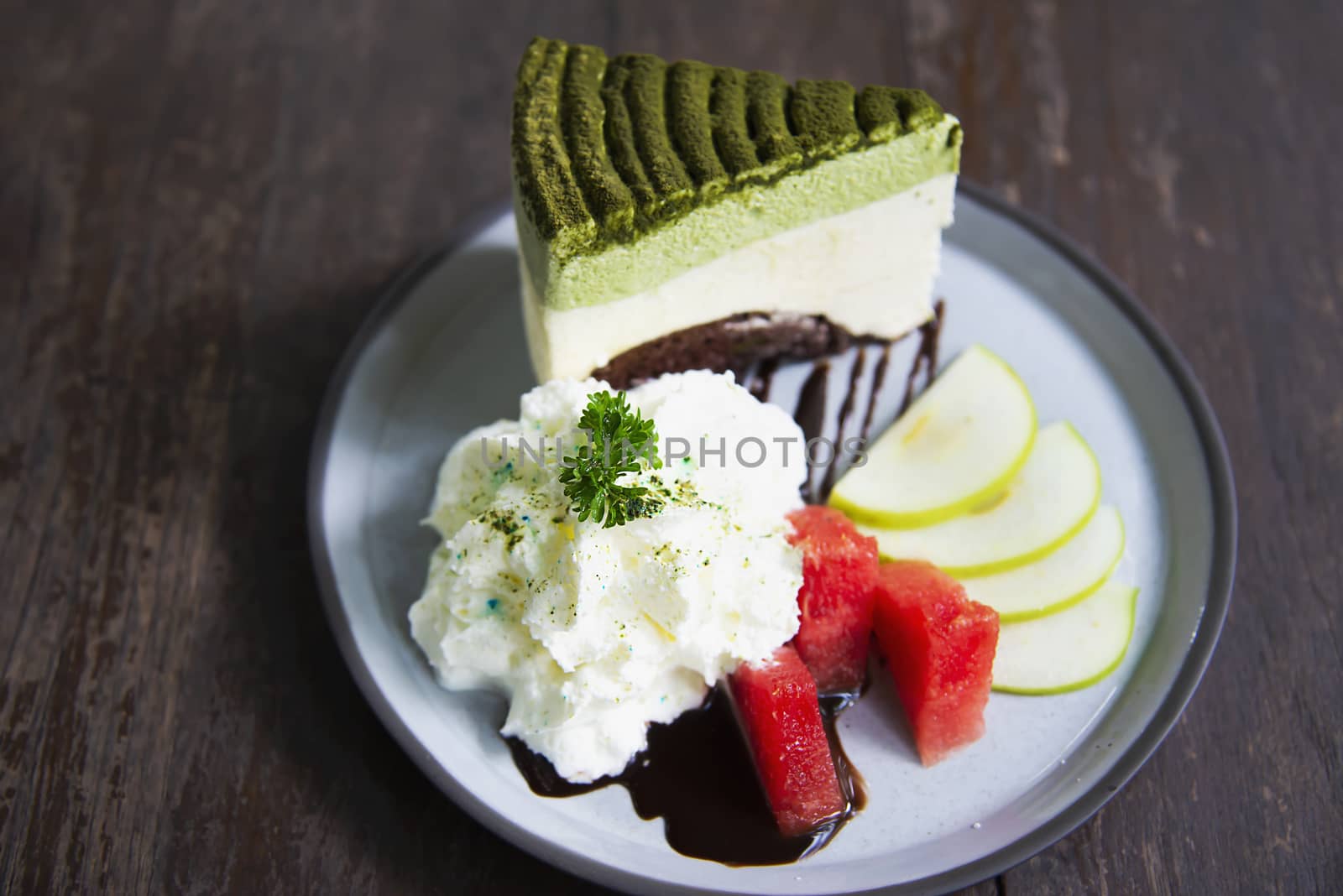 Colorful green tea favor cake with well decorated fruit pieces and whipped cream in white plate - cake recipe menu concept by pairhandmade