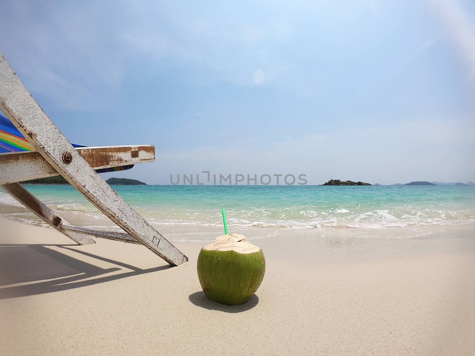 Relax beach chair with fresh coconut on clean sand beach with blue sea and clear sky - sea nature background relax concept by pairhandmade