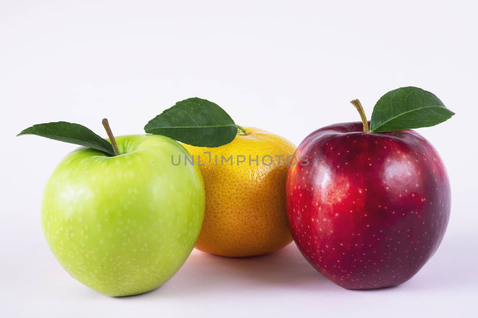 Fresh red green apple and orange over soft pink background - fresh fruit background concept