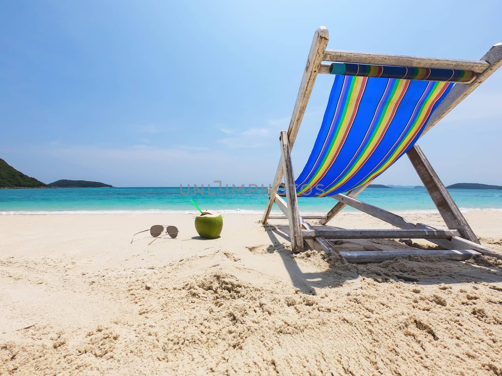 Relax beach chair with fresh coconut on clean sand beach with blue sea and clear sky - sea nature background relax concept