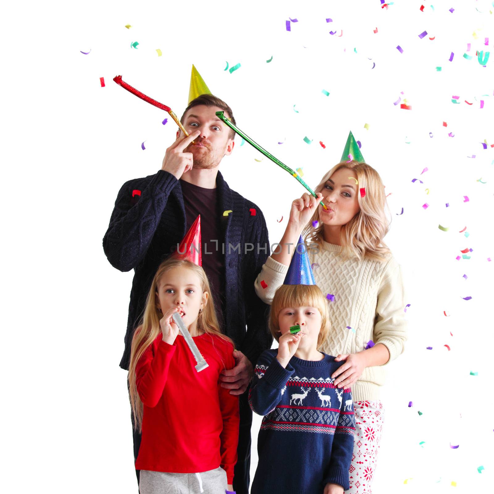 Family blowing party trumpets with confetti celebrating new year