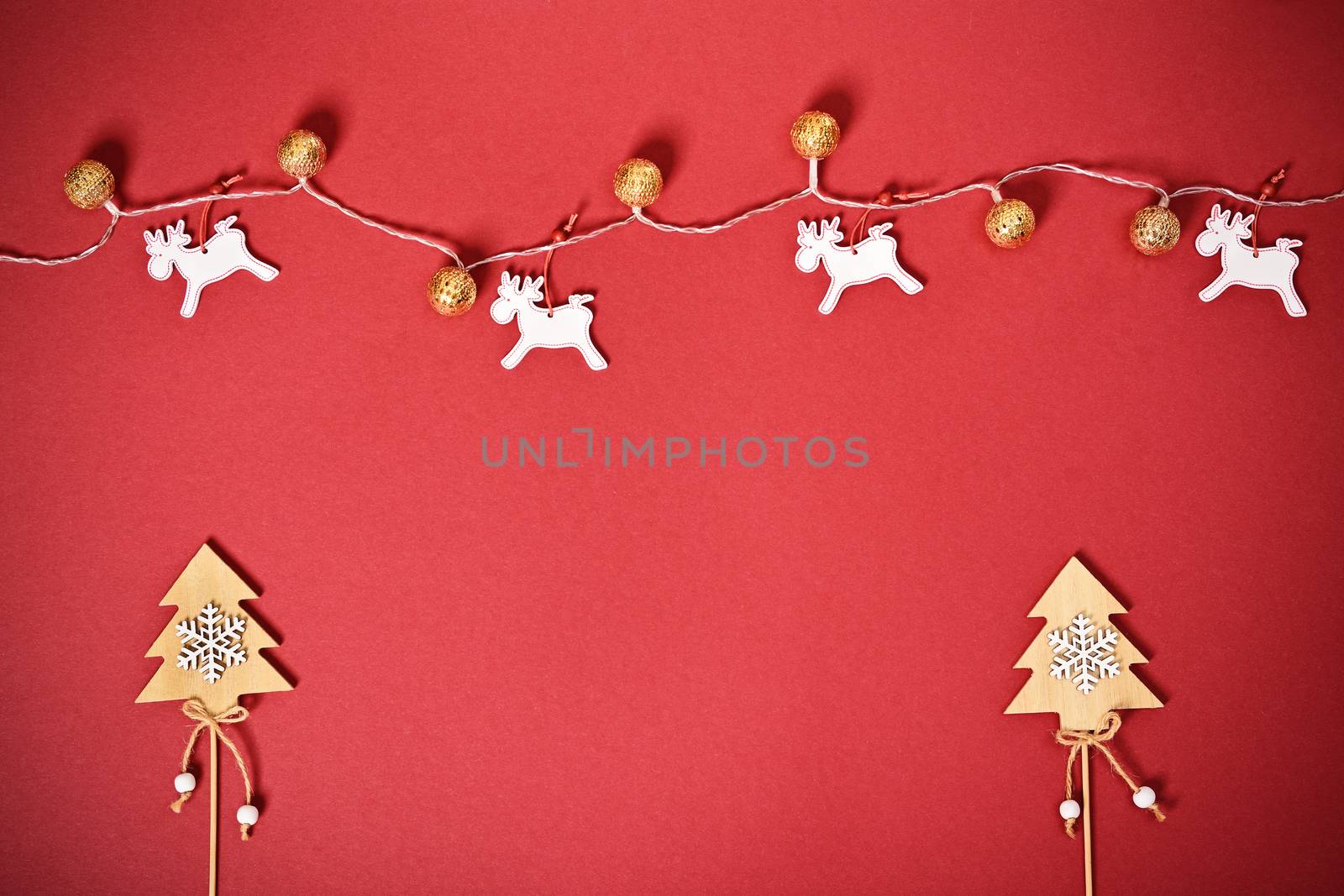 Christmas and New Year composition. Seasonal greeting card concept with Christmas trees, lights and reindeer on red background. Christmas, winter, new year concept. Flat lay, top view, copy space.