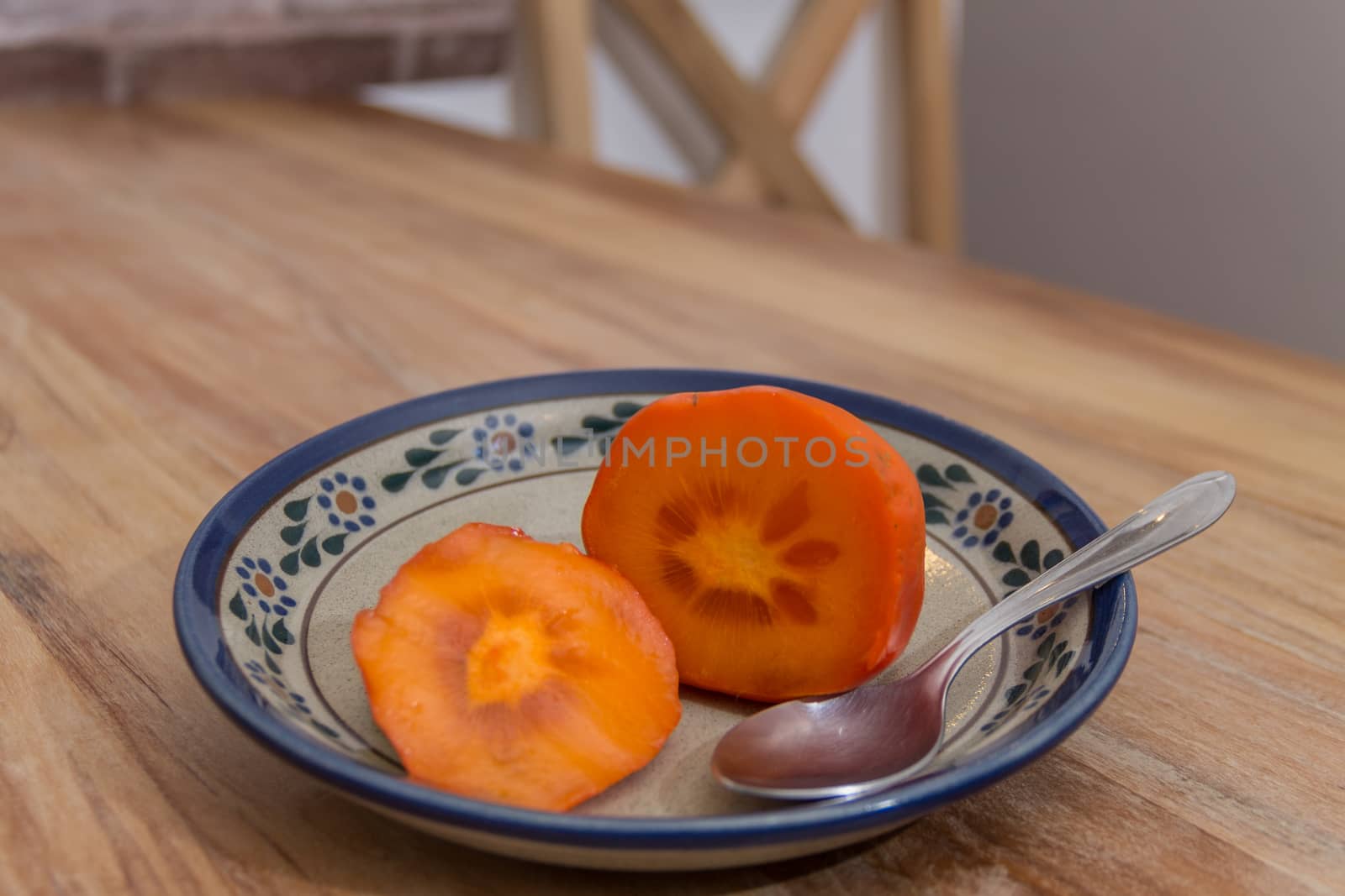 Persimmon ready to eat on rustic plate by leo_de_la_garza