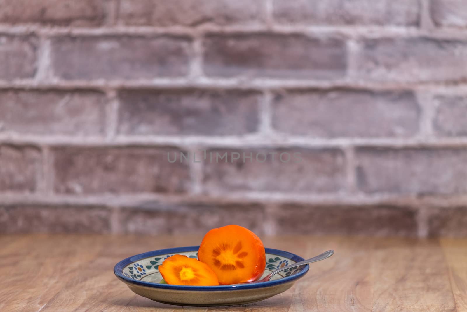 Persimmon ready to eat on rustic plate by leo_de_la_garza