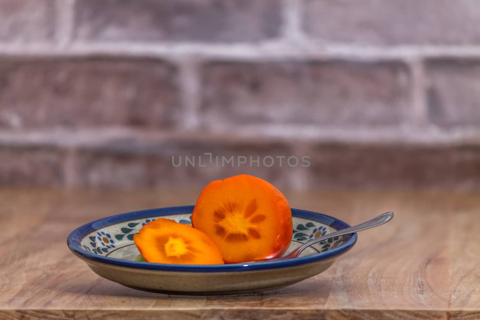 Persimmon ready to eat on rustic plate by leo_de_la_garza