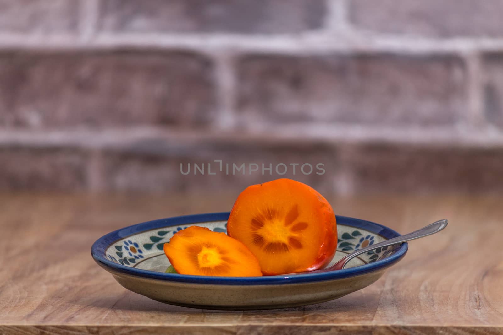 Persimmon ready to eat on rustic plate by leo_de_la_garza
