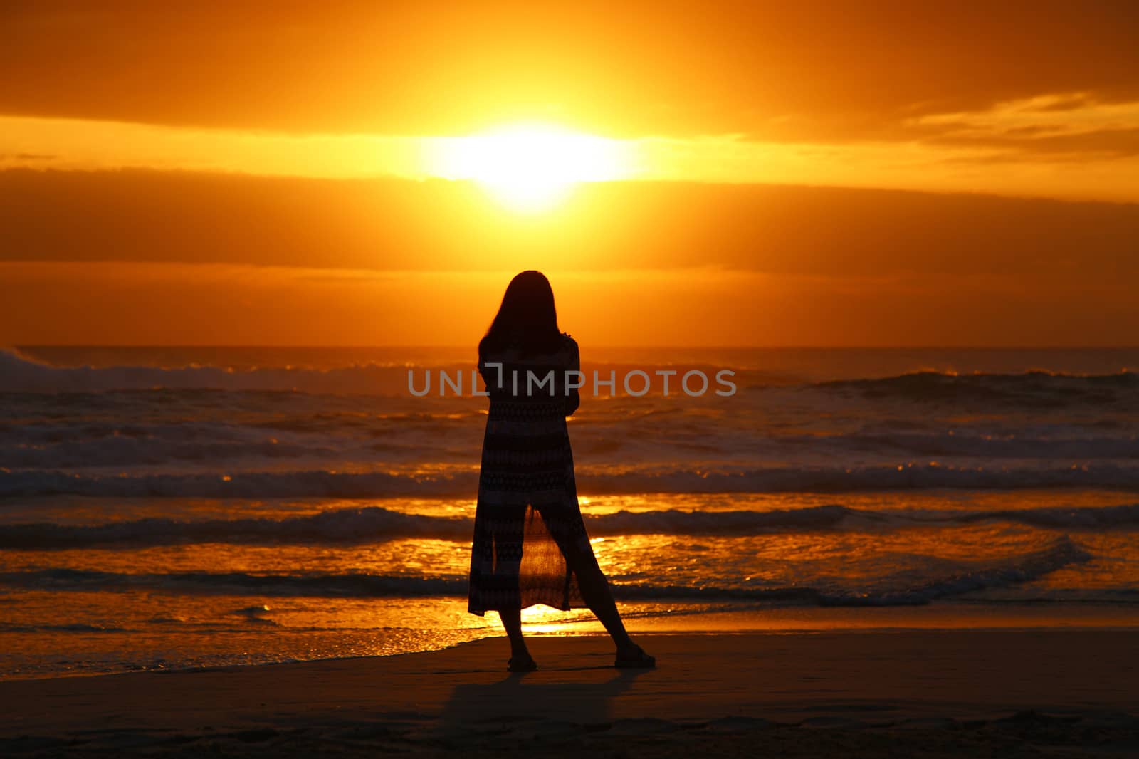 Silhouette of a single woman watching the sunrise.