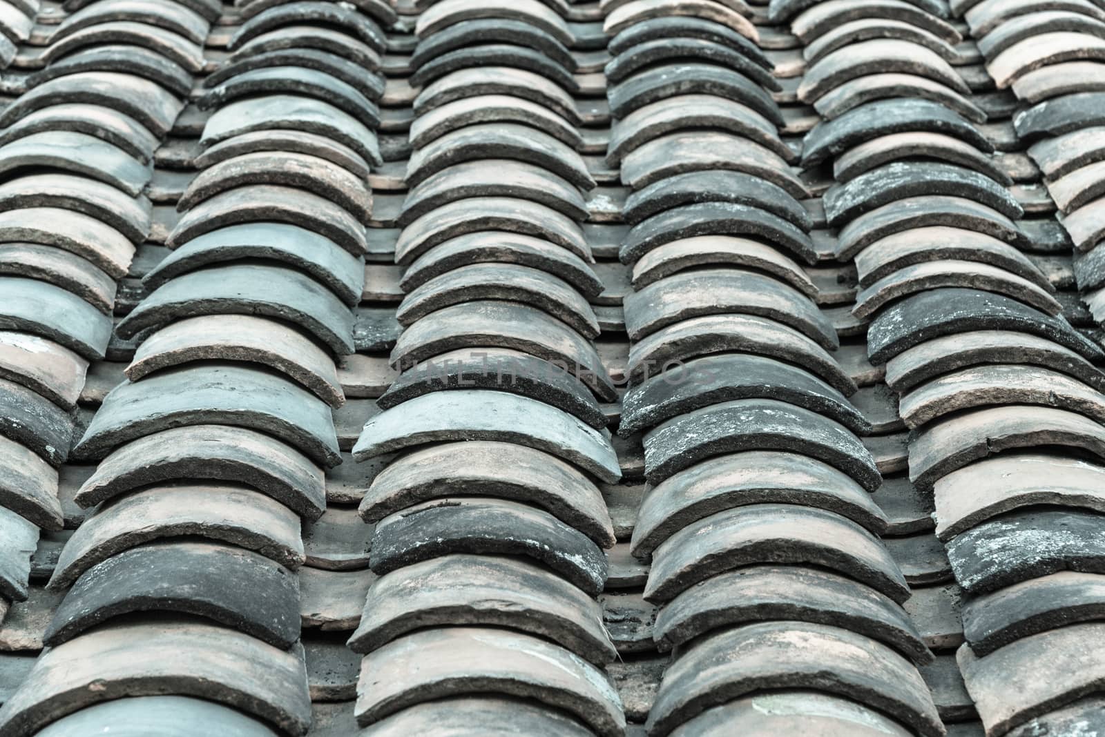 Close-up view curved clay tiled roof in various colors from an old house in North Vietnam, late afternoon light. Ancient, weathered roof tile surface, moss texture. Natural seamless pattern background