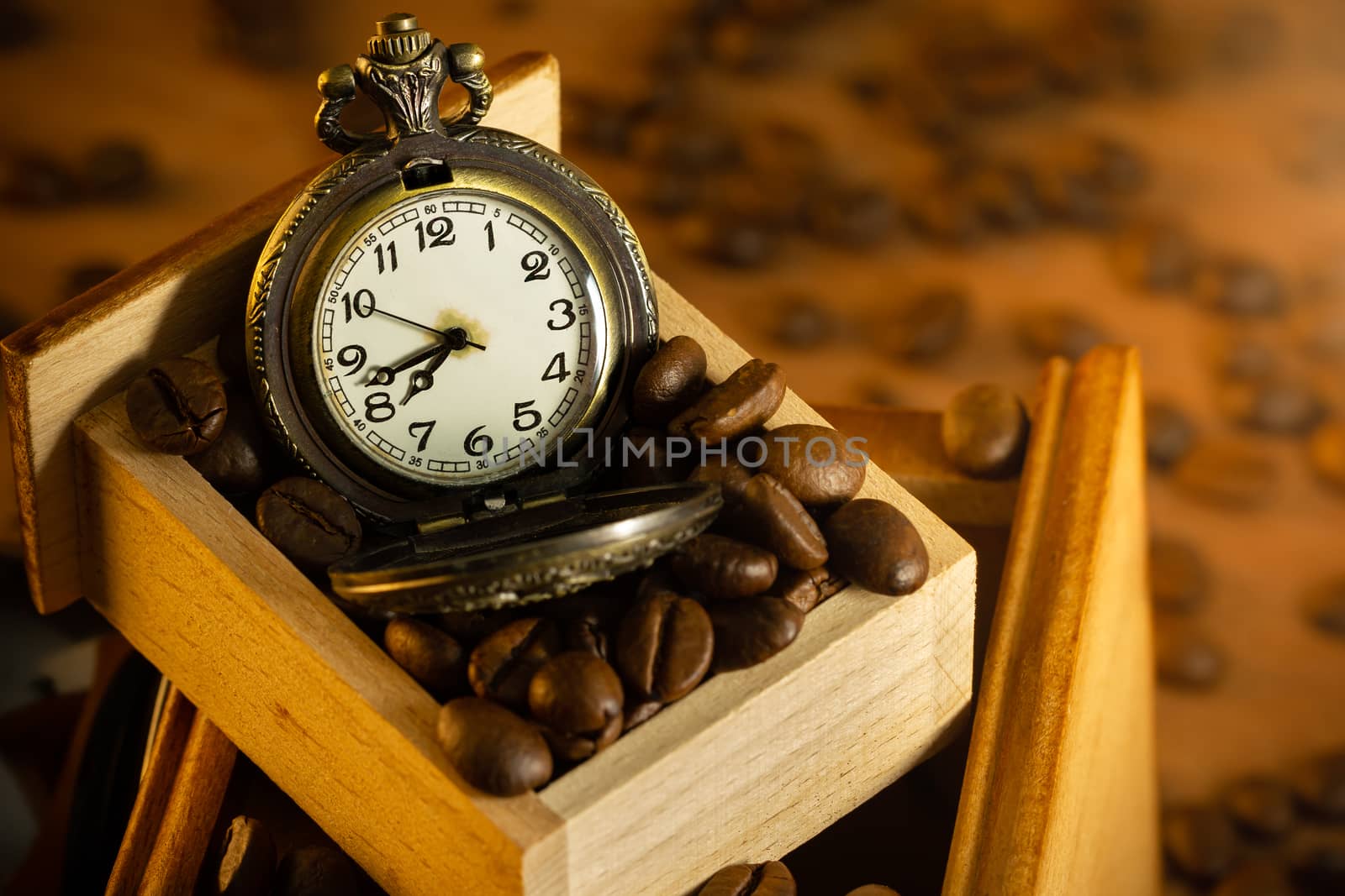 Coffee bean and pocket watch in manual grinder on table. by SaitanSainam