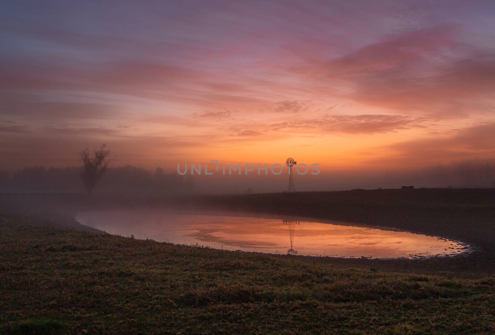 Red skies at dawn with light mist across rural farmlands by lovleah