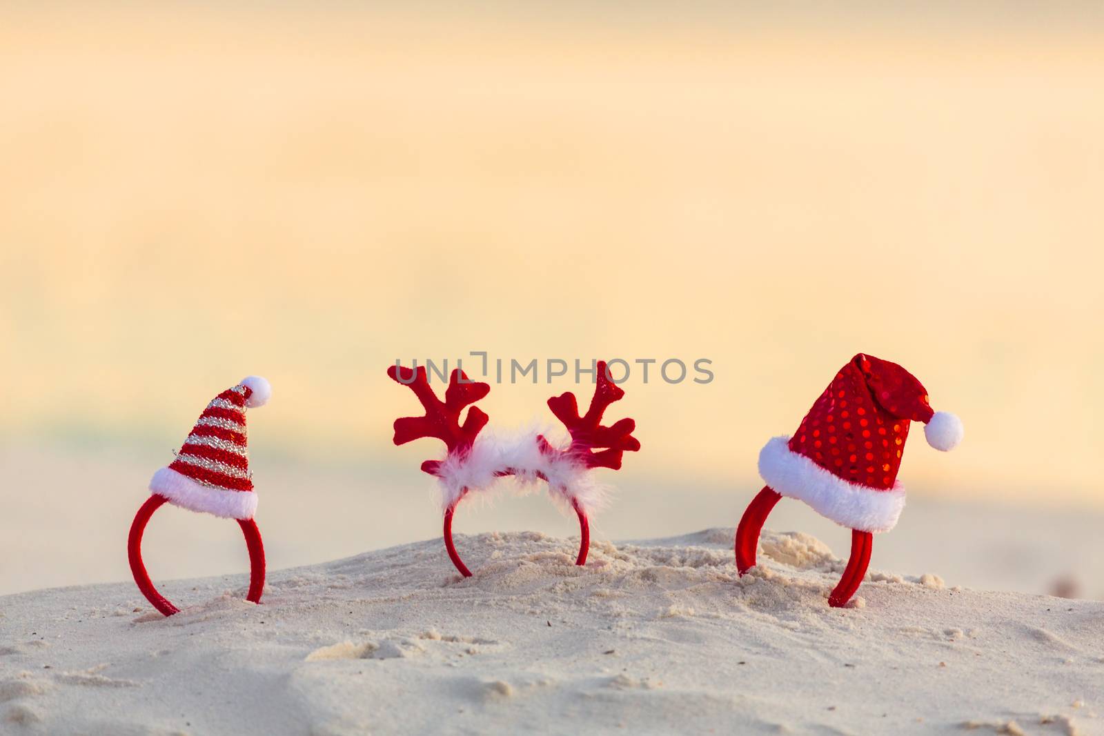 Christmas Santa Hats and reindeer antler headbands standing in the sand on a beach in summer. Beach party, Christmas party.  Copyspace
