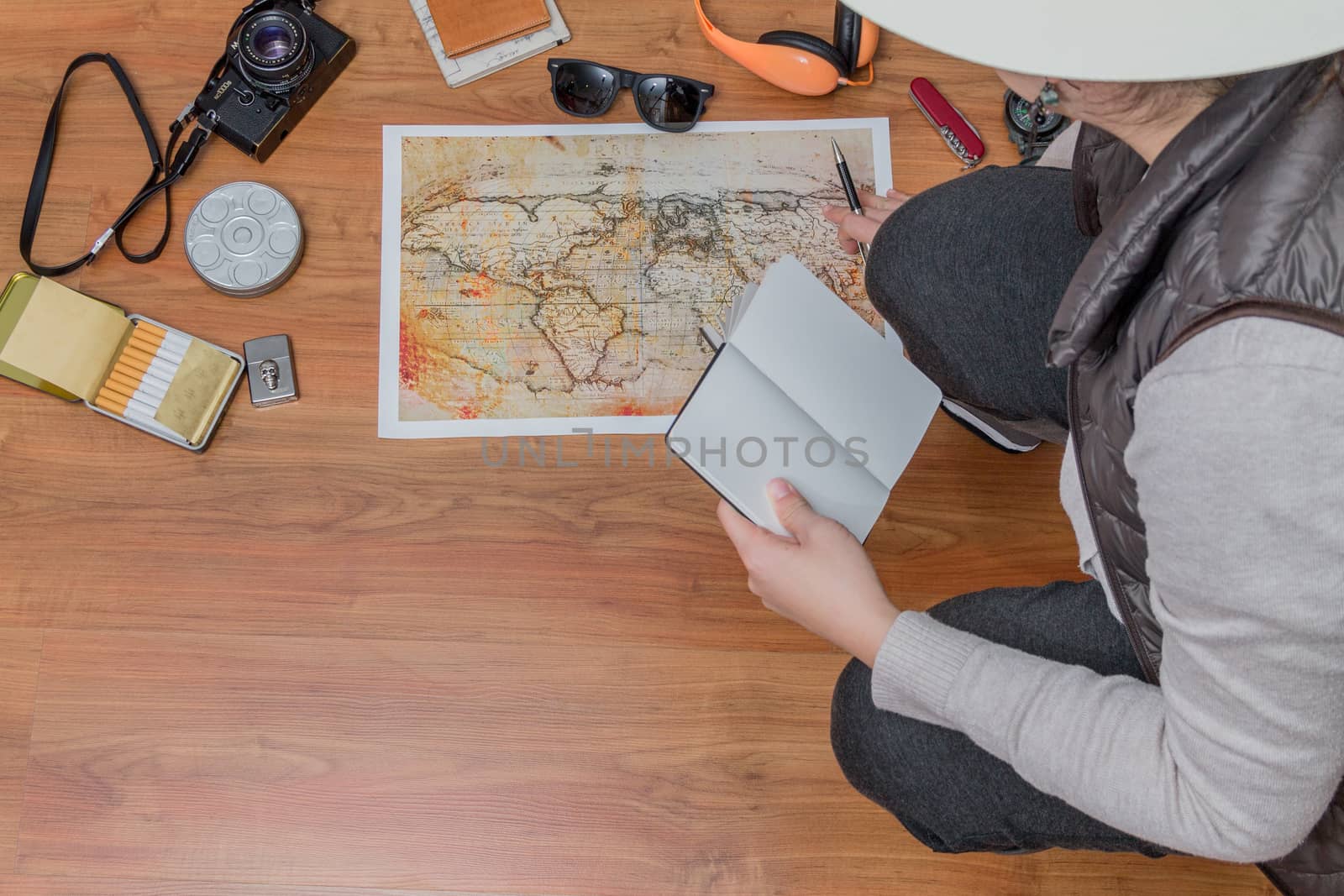 Lady planing a trip with a map and travel assets