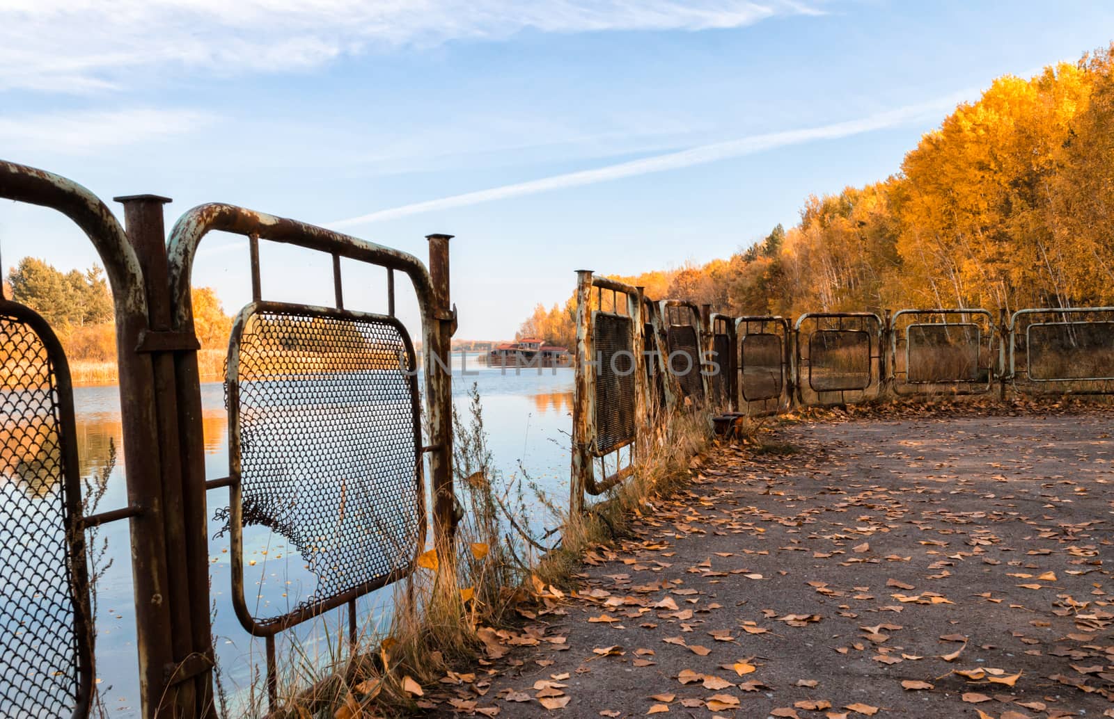 autumn landscape river and pier with an iron fence with a sunken destroyed house in Chernobyl in Ukraine