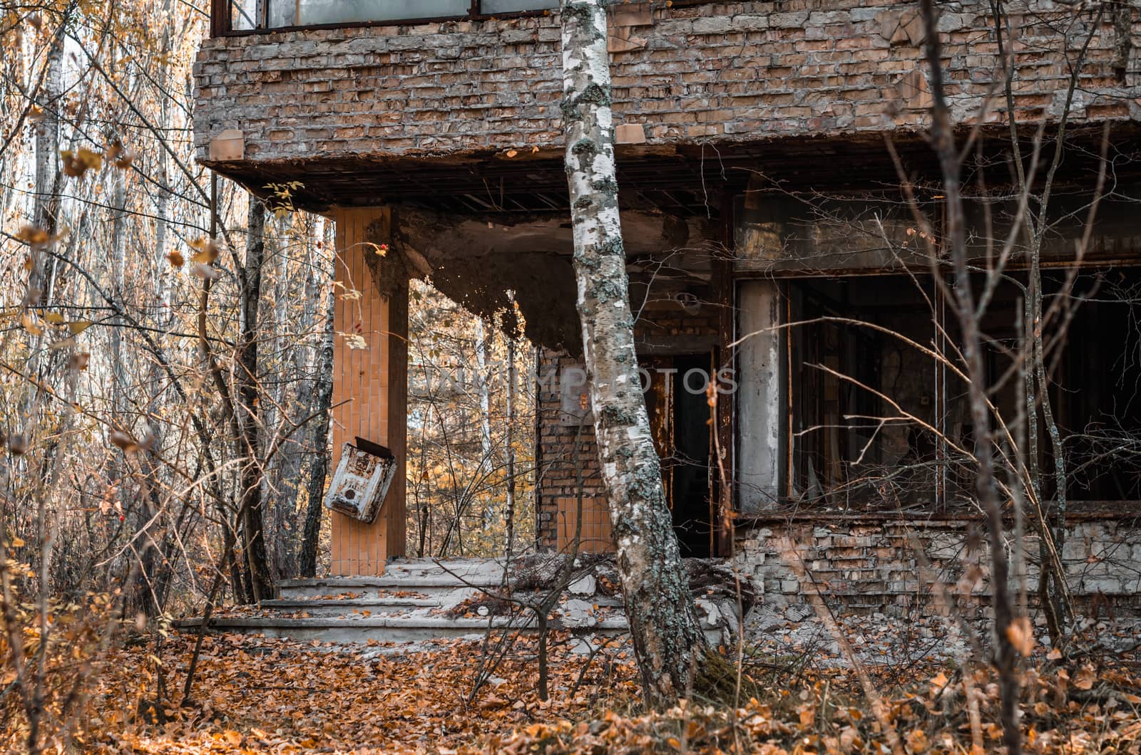 ruins brick house with broken windows and trees in the abandoned city of Chernobyl Ukraine in autumn