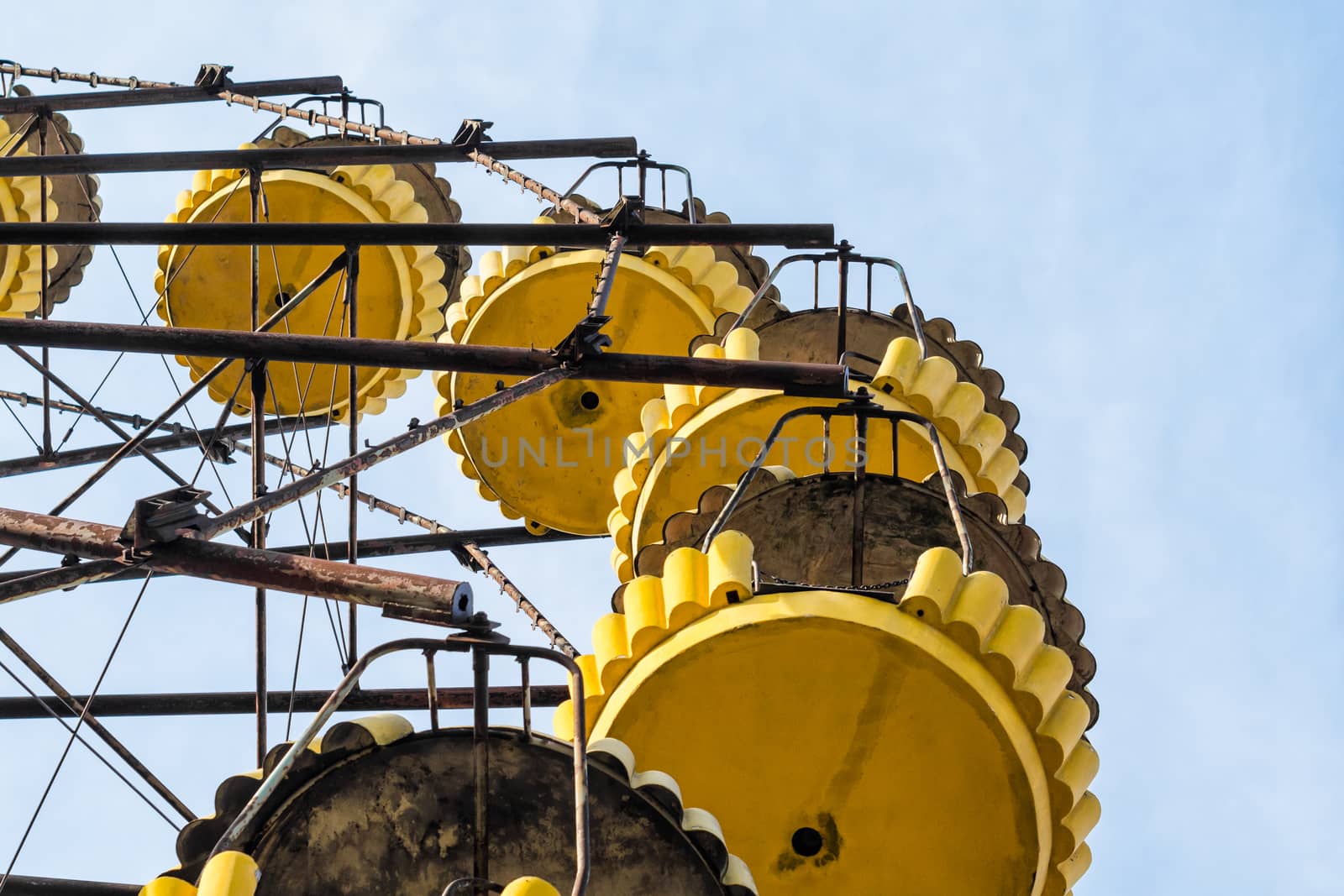 no people carousel cabins in an abandoned amusement park on a background of blue sky and clouds in Chernobyl Ukraine