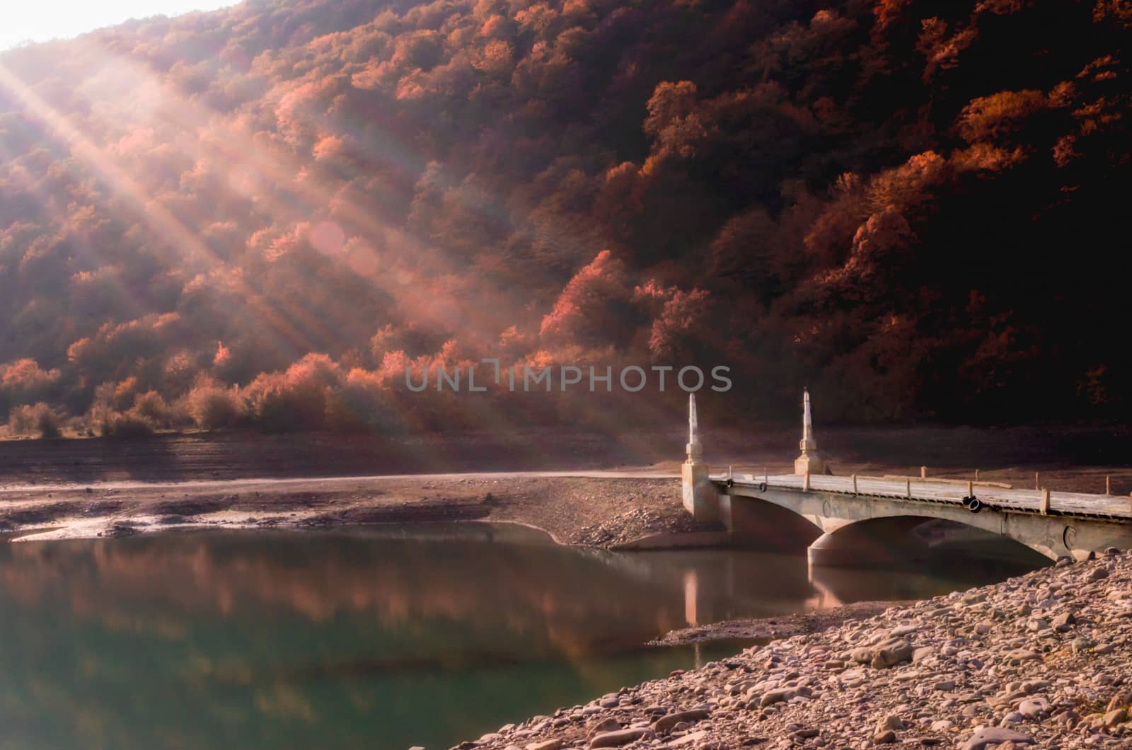 old vintage stone bridge over the river on a background of mountains with trees in Georgia in autumn