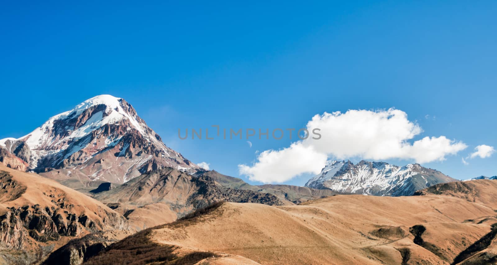 wallpaper high cliffs and mountains with snow on tops against a blue sky and clouds in Georgia in the autumn afternoon