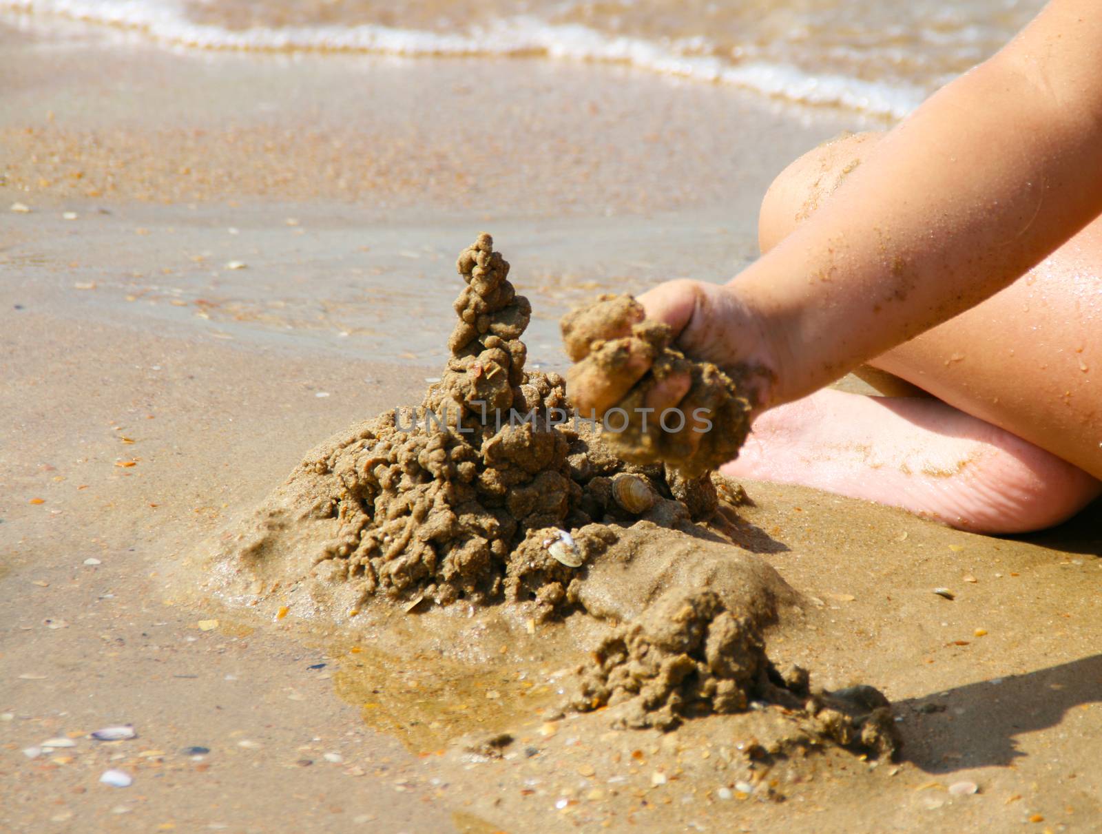 Child sculpts a pyramid of sand on the beach. by Igor2006