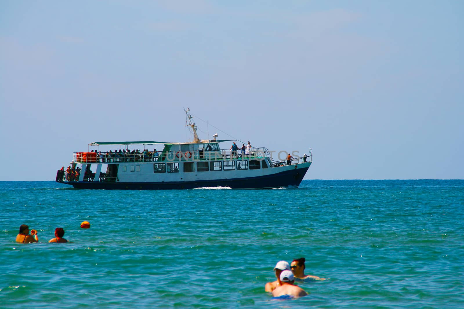 Pleasure boat on the background of bathing people in the sea.