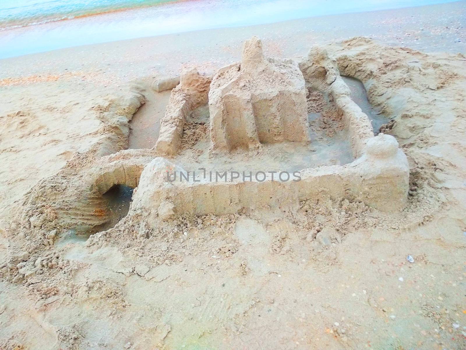 
Sculpture of a building made of sand on the beach.