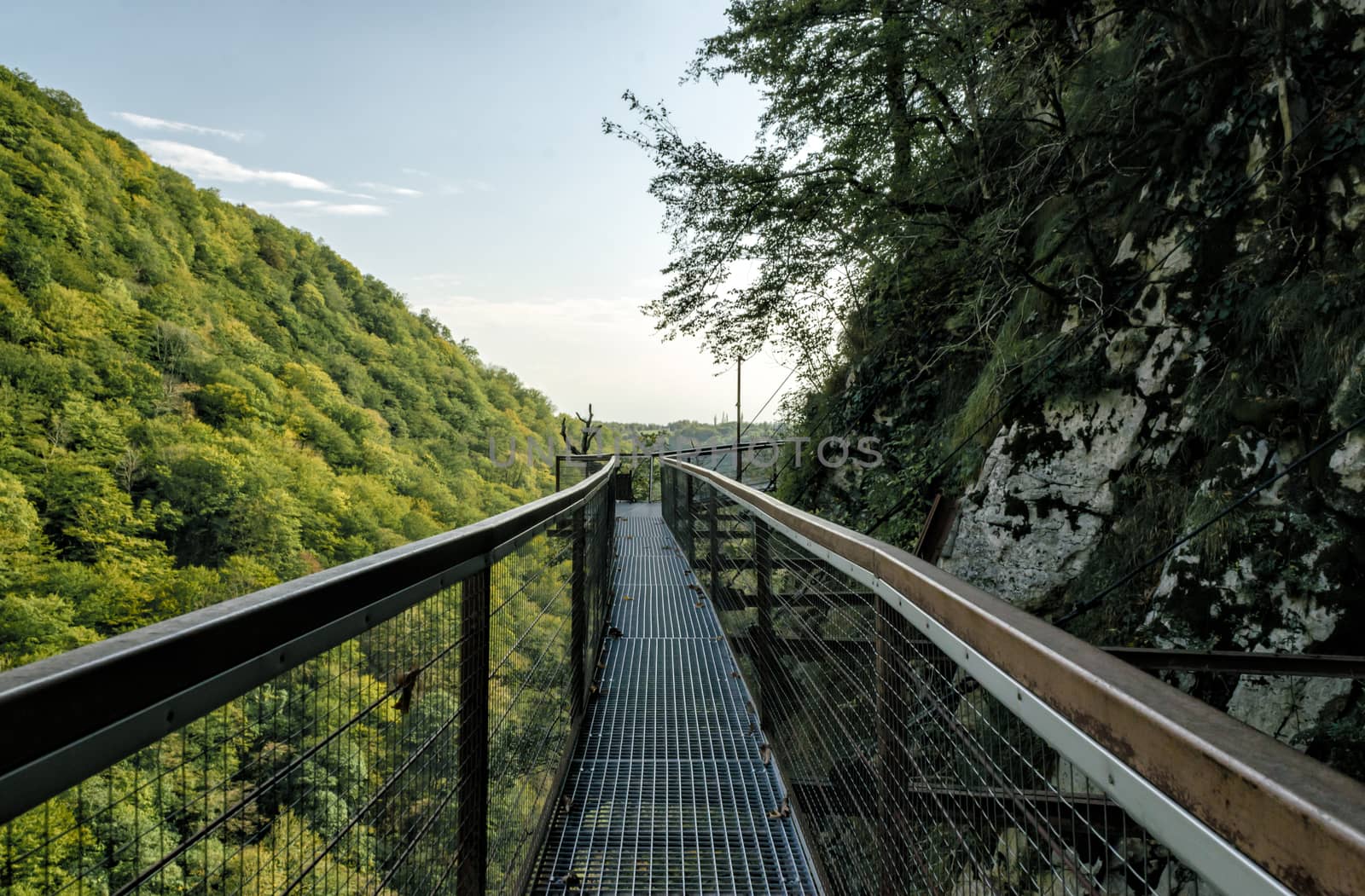 long safe tourist metal bridge in Okatse canyon in Georgia in autumn against mountains and forest and sky with clouds
