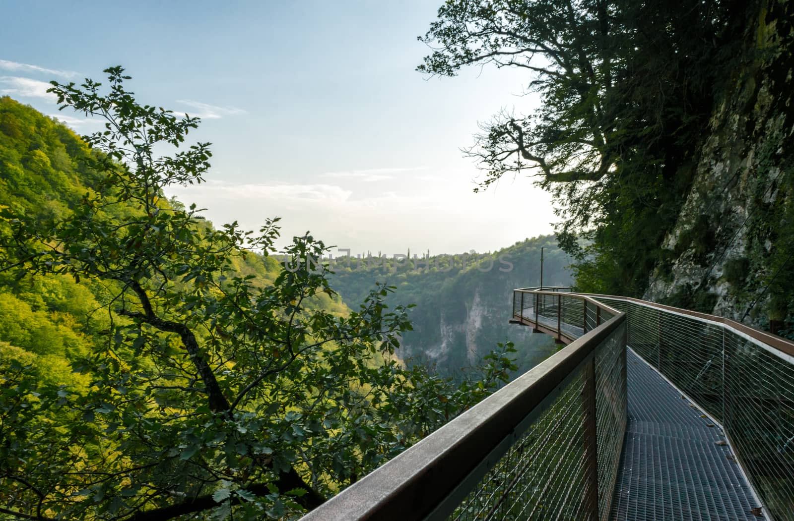 long safe metal bridge in canyon in Georgia in autumn against mountains and forests