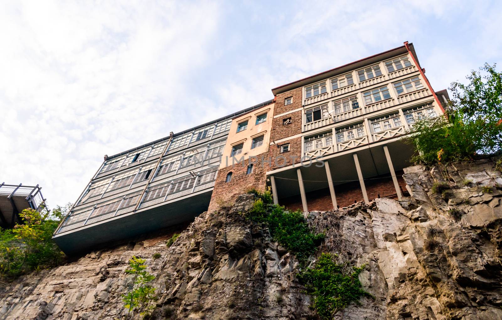 modern and old house high on a cliff against a sky with clouds in Tbilisi Georgia