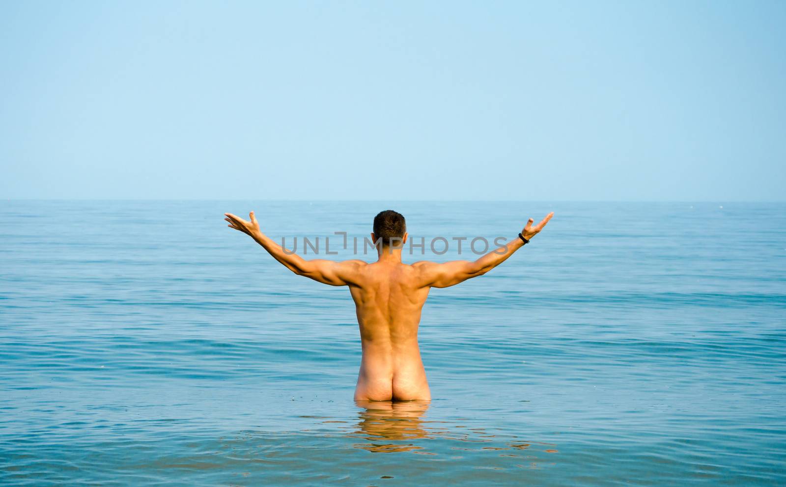 nude young man in blue water