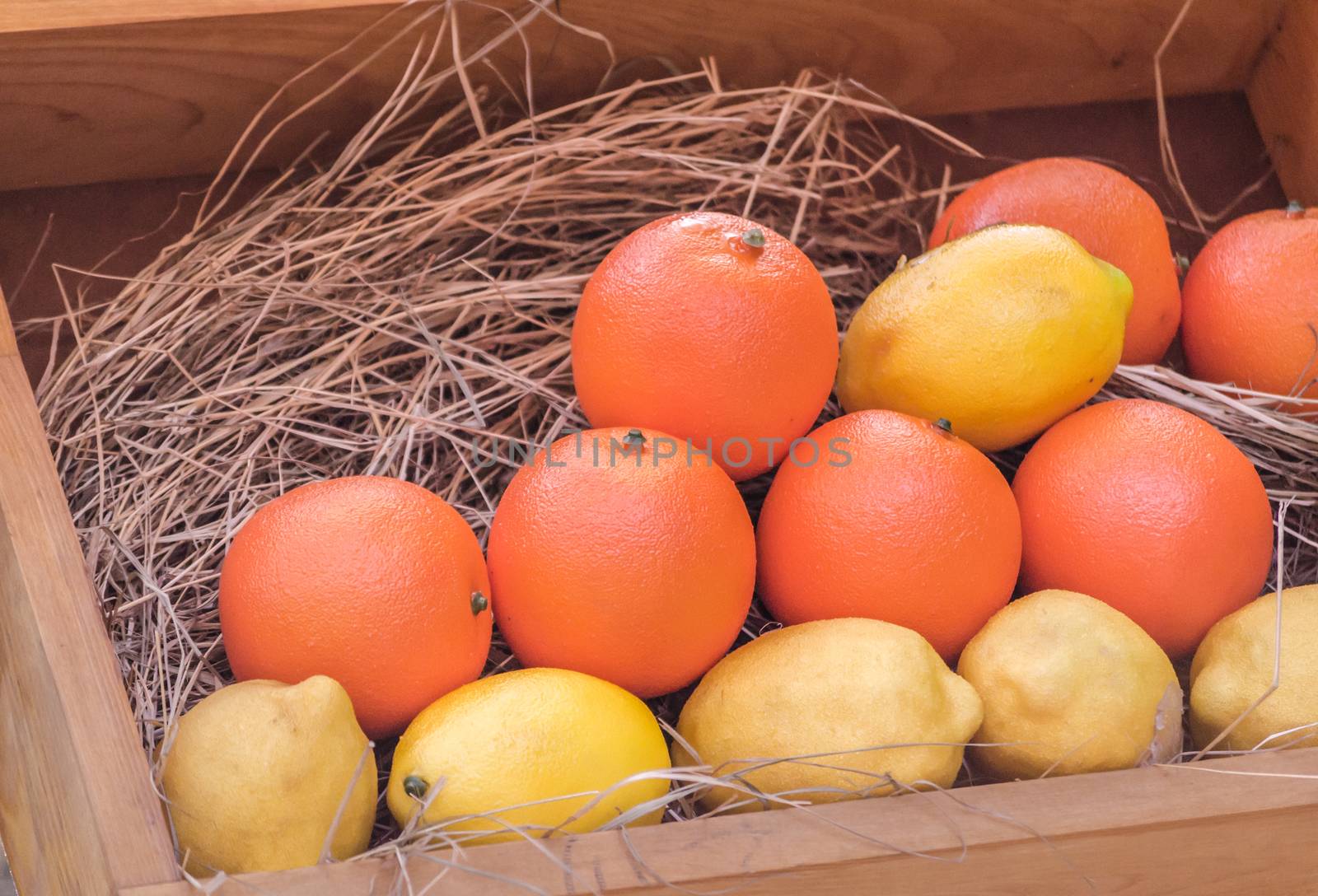 ripe yellow lemons and orange oranges in a wooden box close up