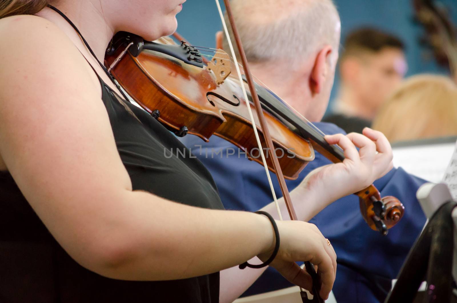 female musician playing a violin with a symphony orchestra