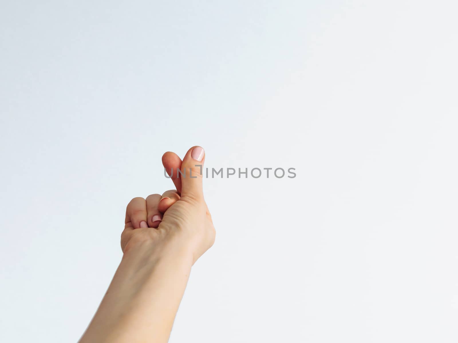 Korean symbol of love with fingers. Female hand depicts heart on white background. Copy space for text or design.