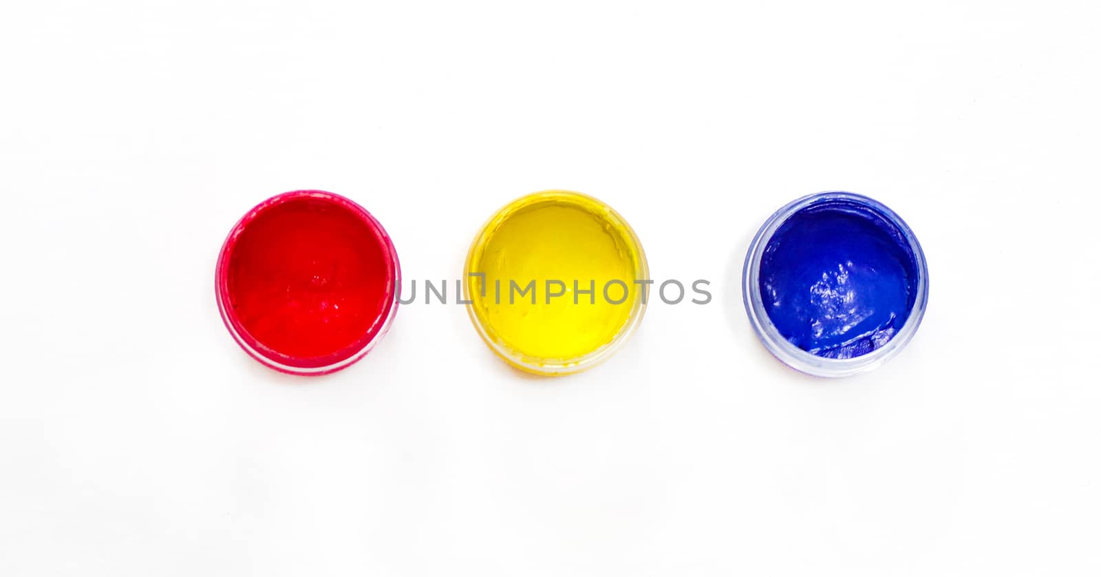 Gouache paint in containers isolated on white background. RGB colors of artistic paint. Red, yellow, blue.