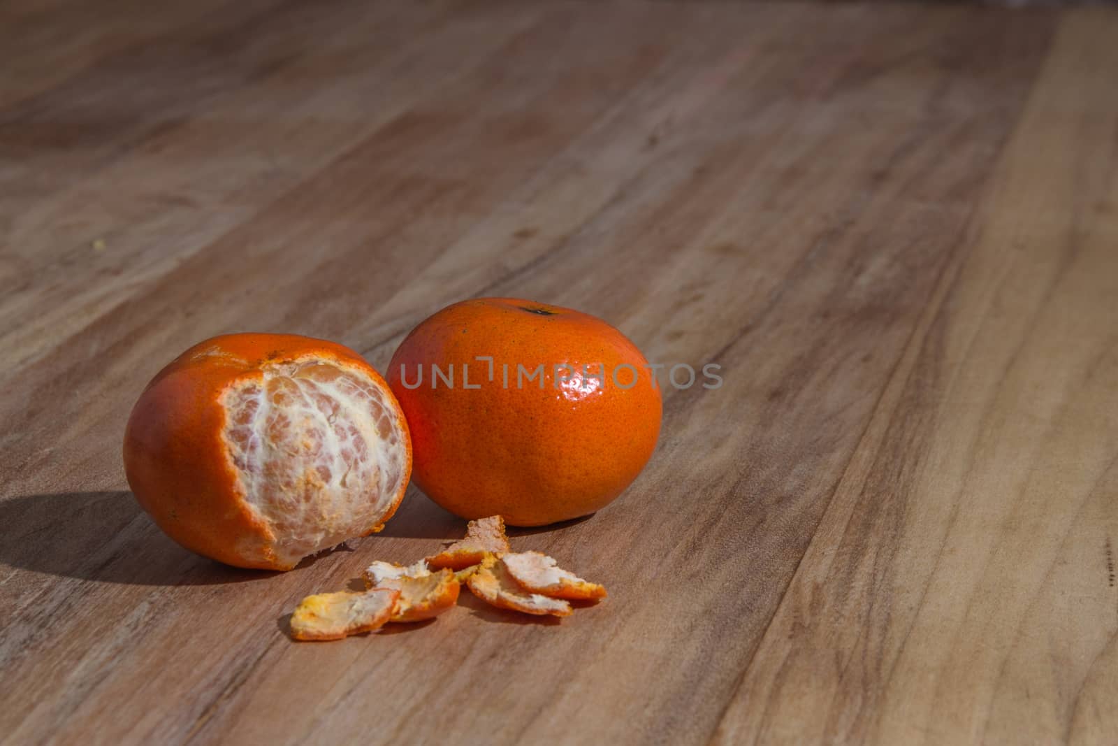 Orange colorful peeled tangerine over wooden table by leo_de_la_garza