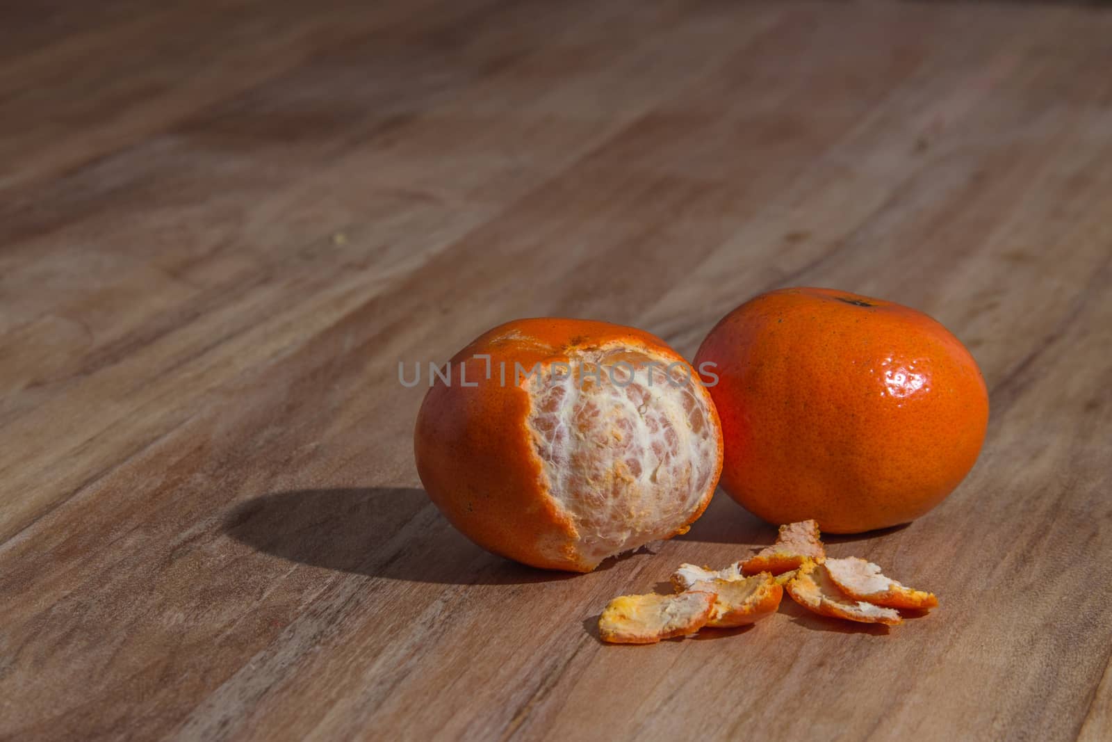Orange colorful peeled tangerine over wooden table by leo_de_la_garza