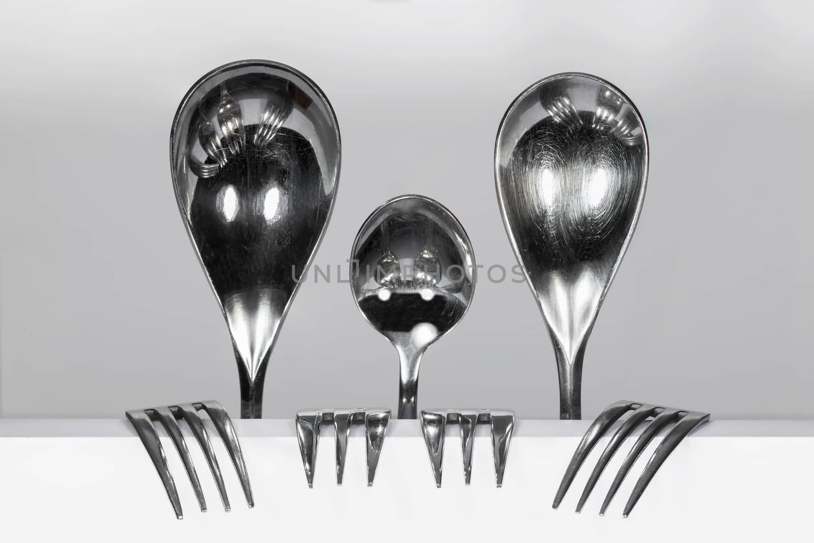 Cuterly Family of three metal spoons and four forks against a white background 
