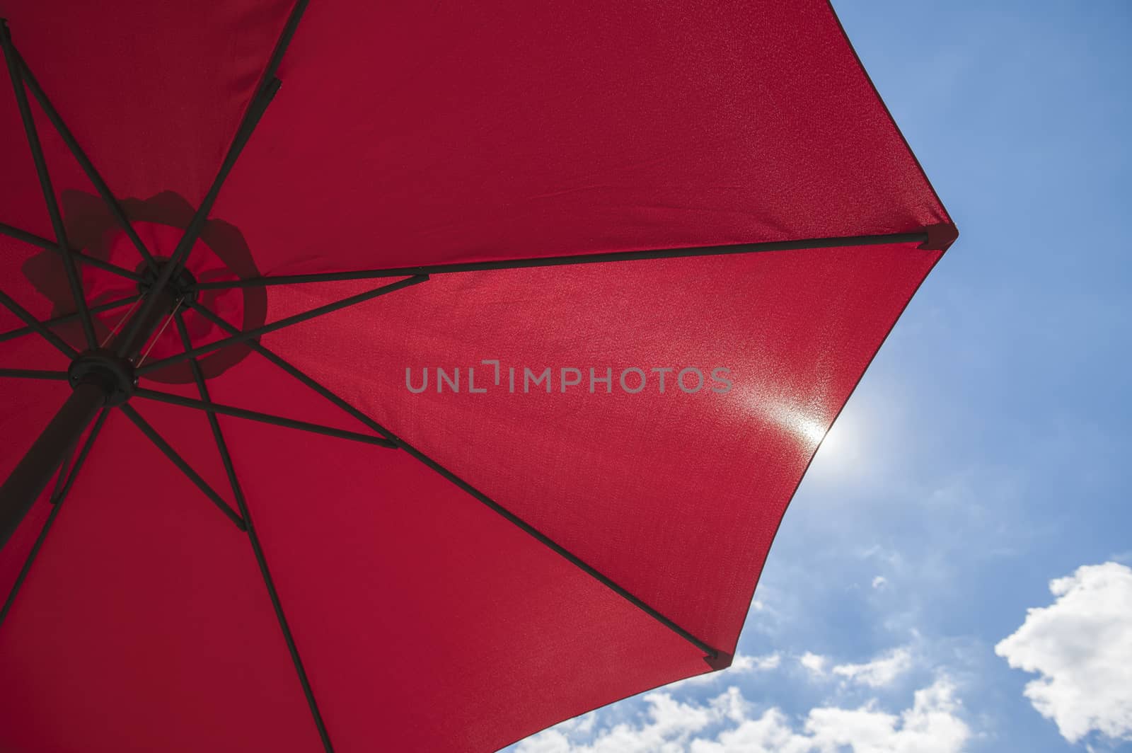 Red beach parasol against a blue sunny summer sky
