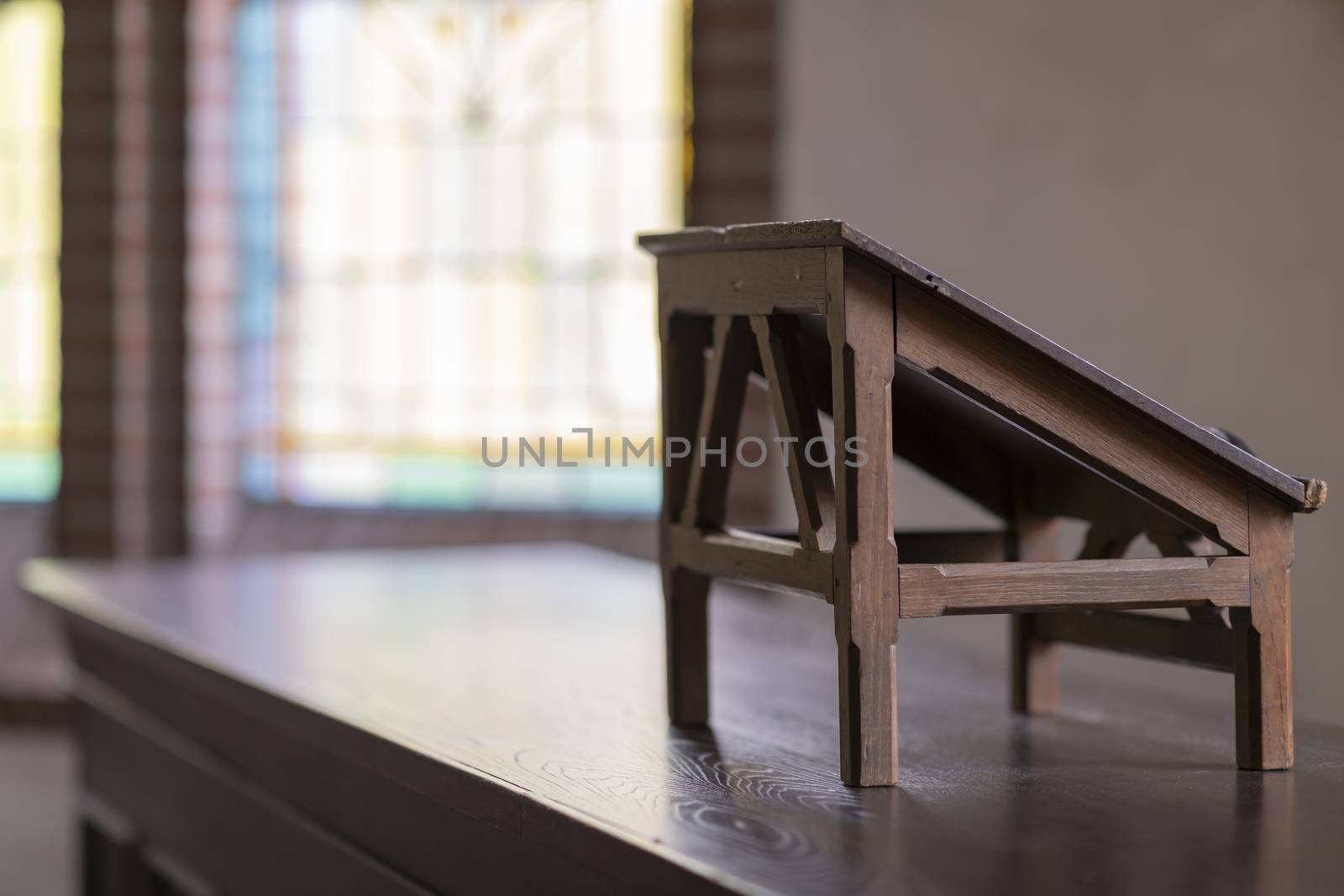 Wooden lectern in an old church with stained glass windows in the background
