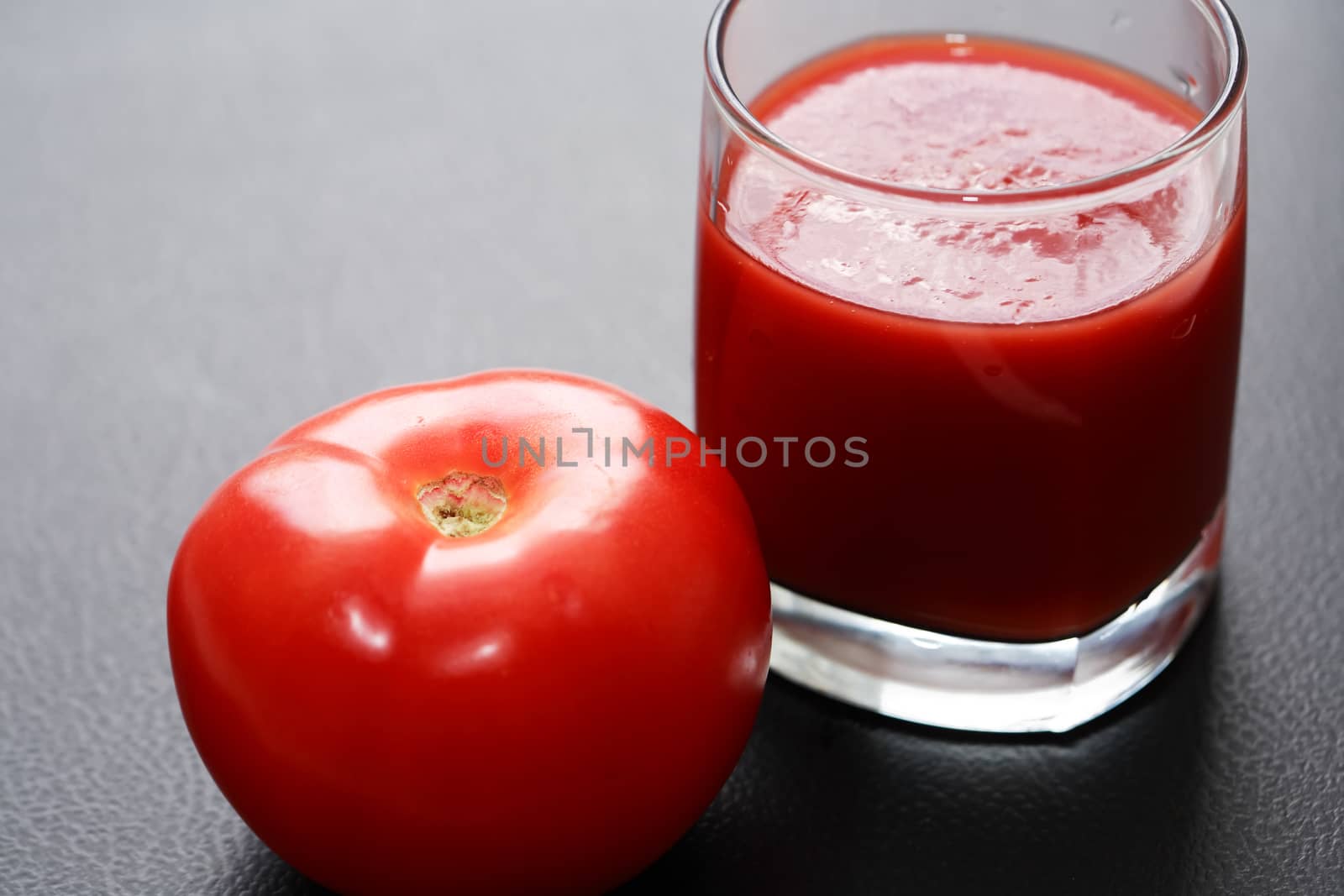 Full glass of tomato juice on nice gray background