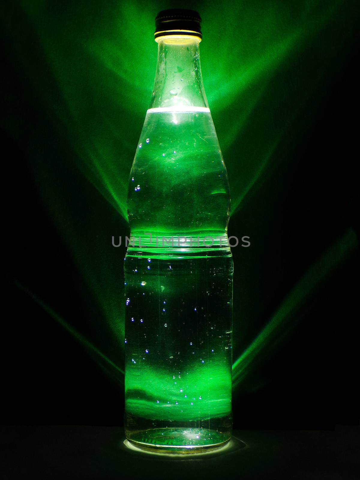 Drink in a glass bottle with green background and backlight. Alcoholic beverage. Harm to health. Healthy lifestyle. A bottle of alcohol and the drops of condensate. Cold drink.