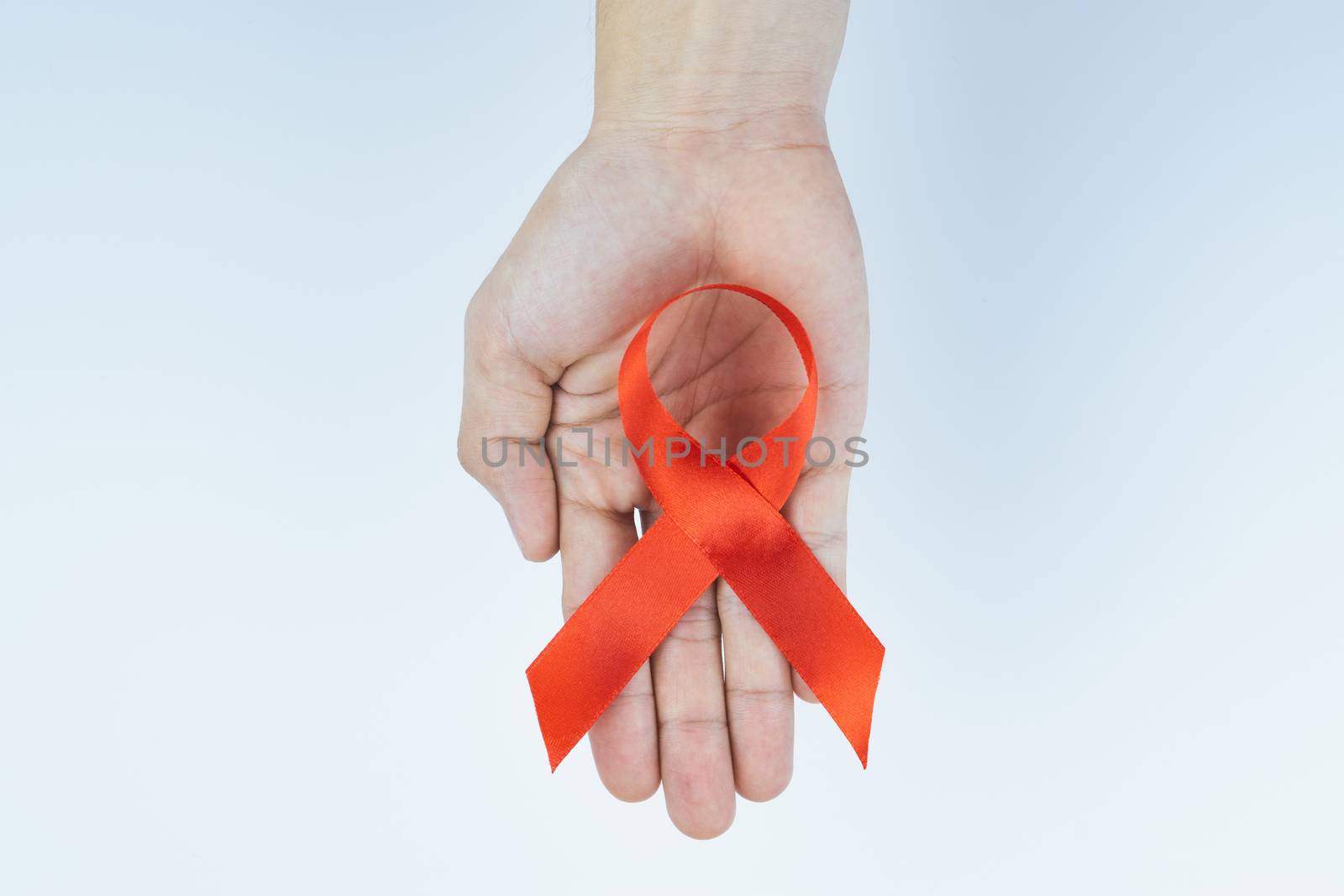 Aids awareness, male hands holding red AIDS awareness ribbon on  by mikesaran