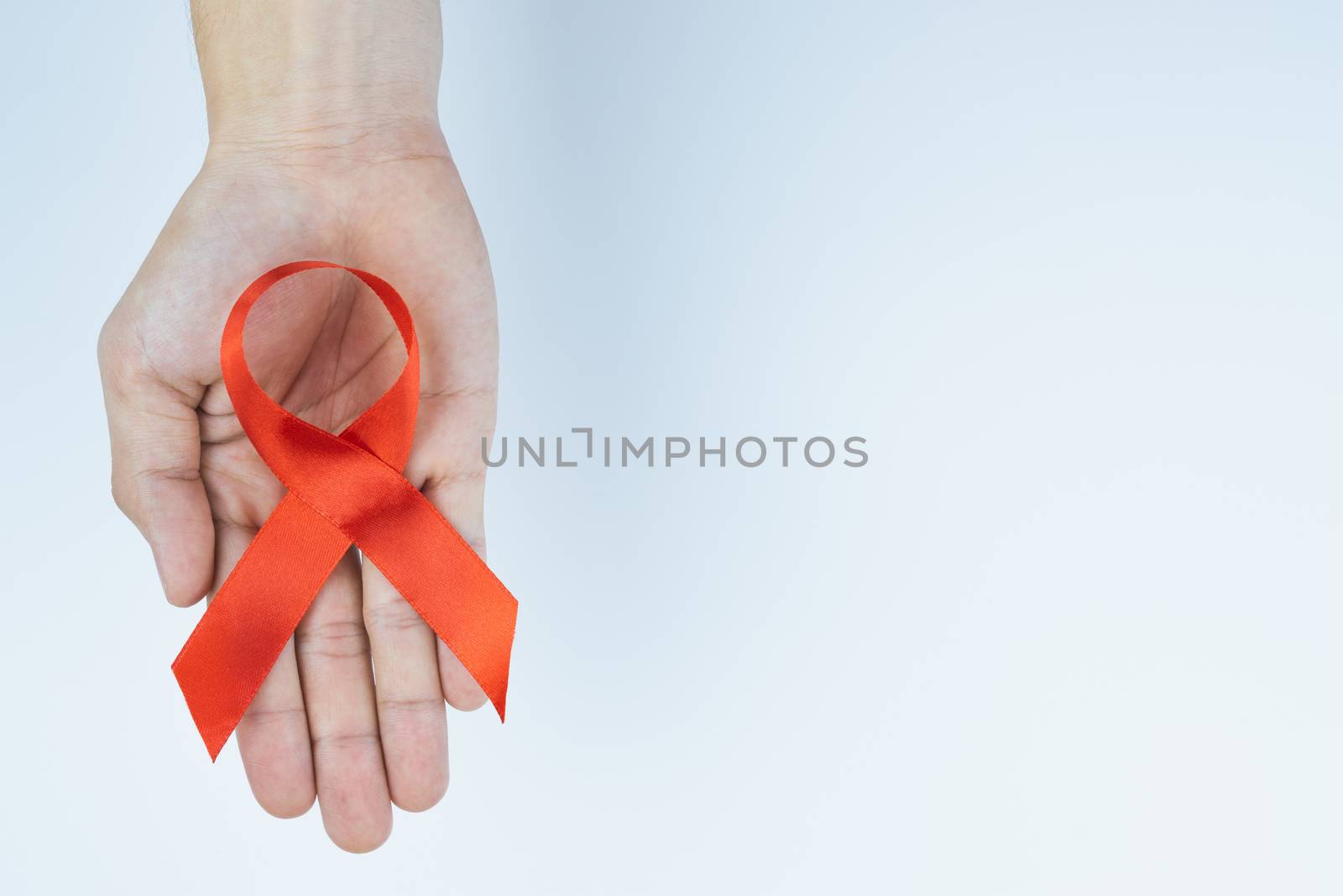 Aids awareness, male hands holding red AIDS awareness ribbon on white background. World Aids Day, Healthcare and medical concept.