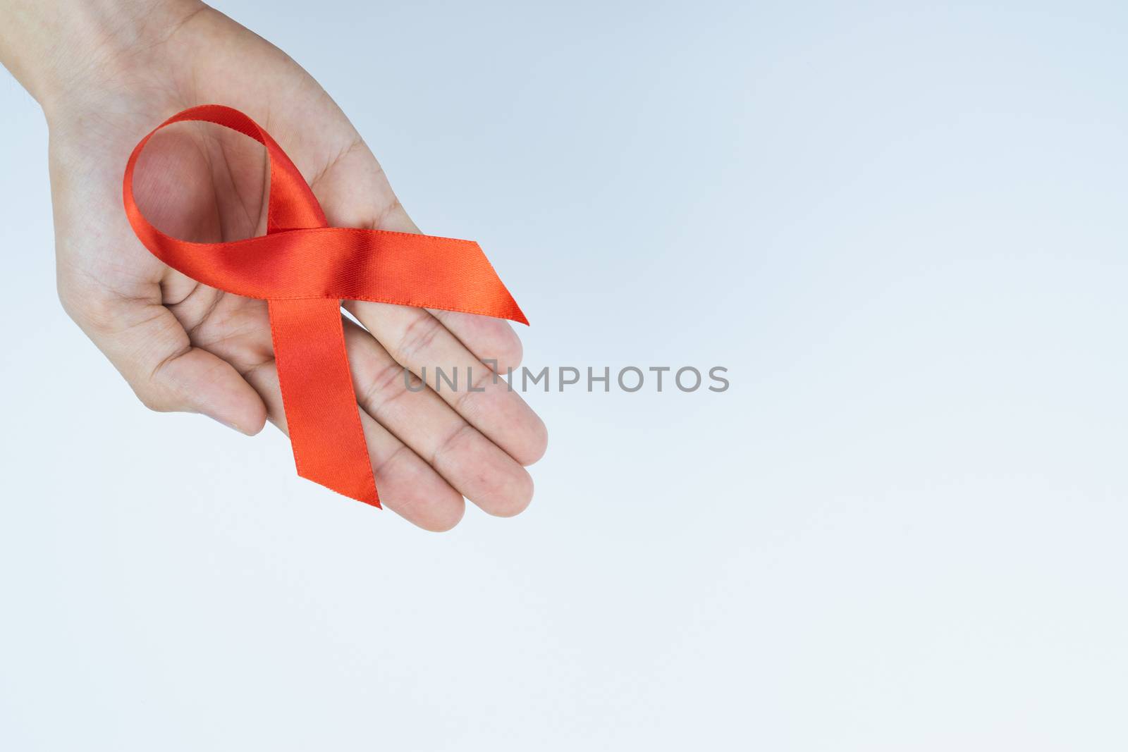 Aids awareness, male hands holding red AIDS awareness ribbon on  by mikesaran