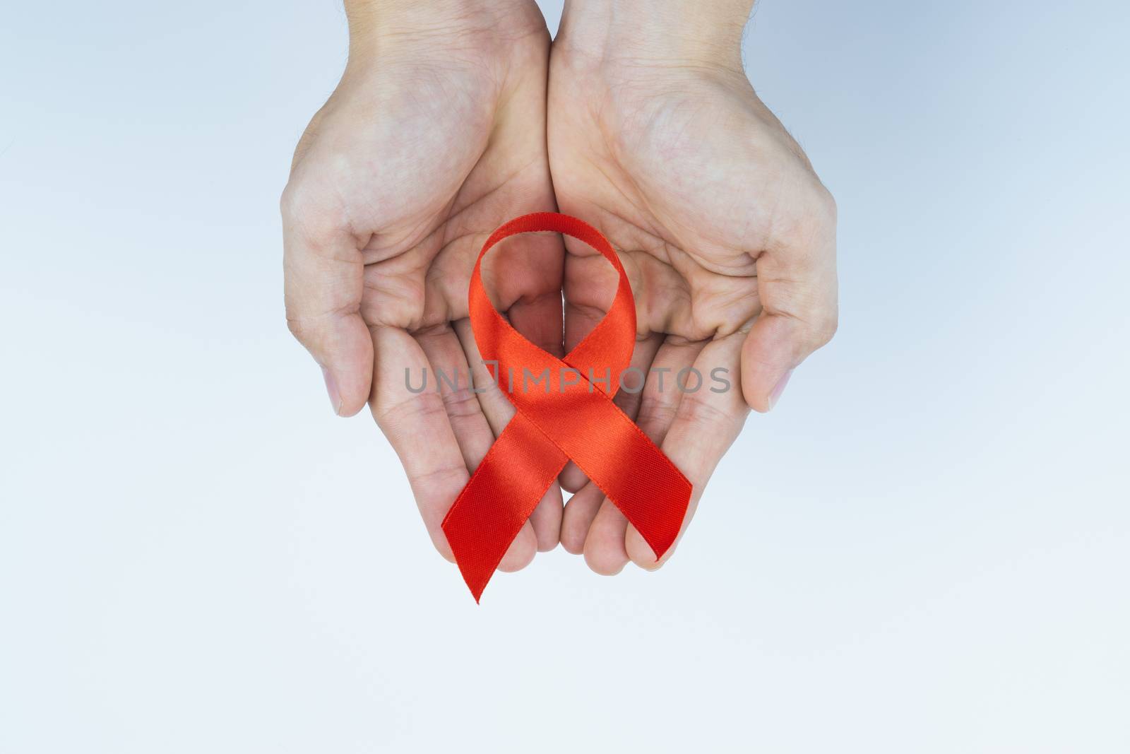 Aids awareness, male hands holding red AIDS awareness ribbon on  by mikesaran