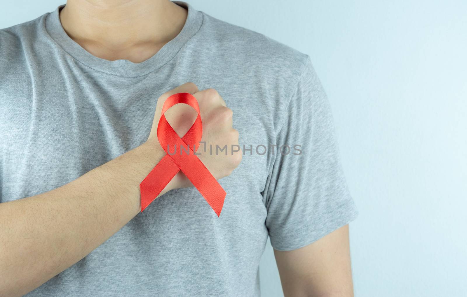 Aids awareness, male hands holding red AIDS awareness ribbon. Wo by mikesaran