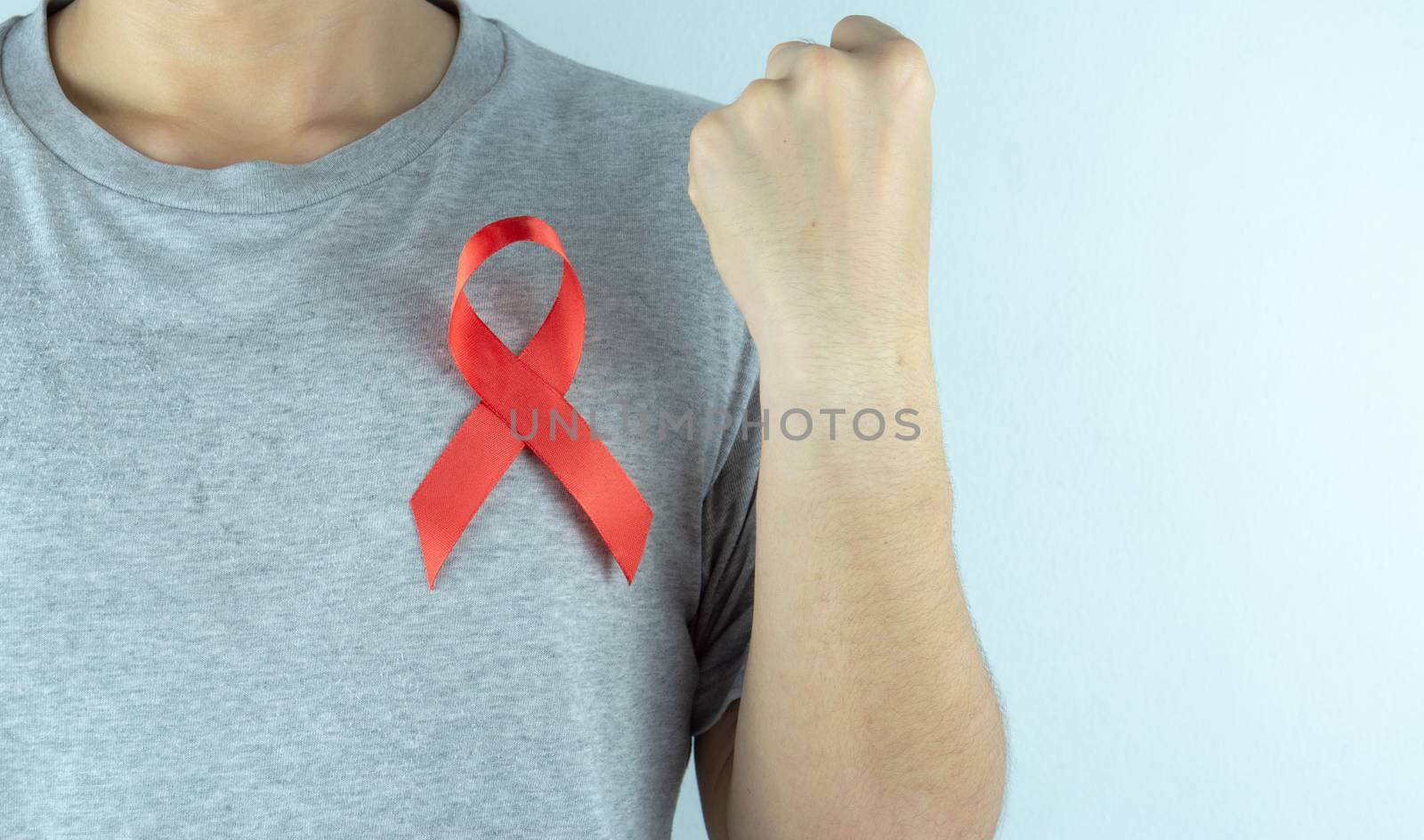 Aids awareness, male hands holding red AIDS awareness ribbon. World Aids Day, Healthcare and medical concept.